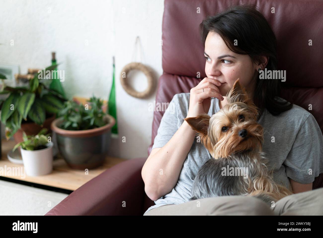 Giovane donna con il cane yorkshire terrier seduto sul divano di casa Foto Stock