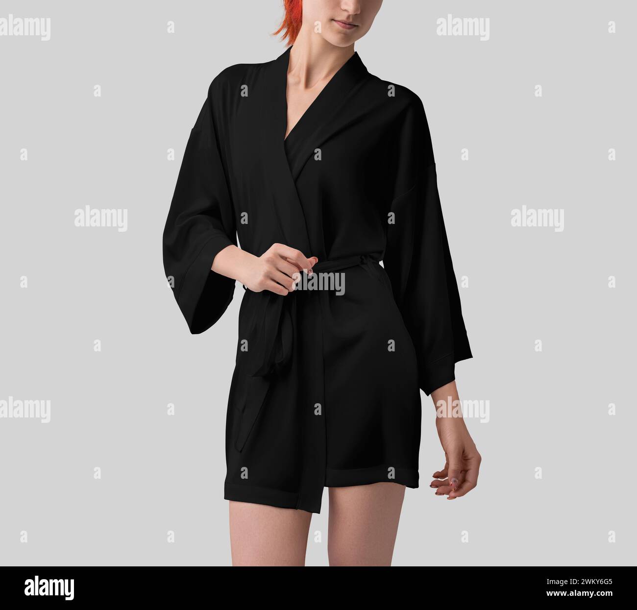 Mockup di abito di seta nero su ragazza dai capelli rossi, vista frontale, kimono con cintura per design, motivo, branding. Modello di abbigliamento per la casa alla moda isolato Foto Stock