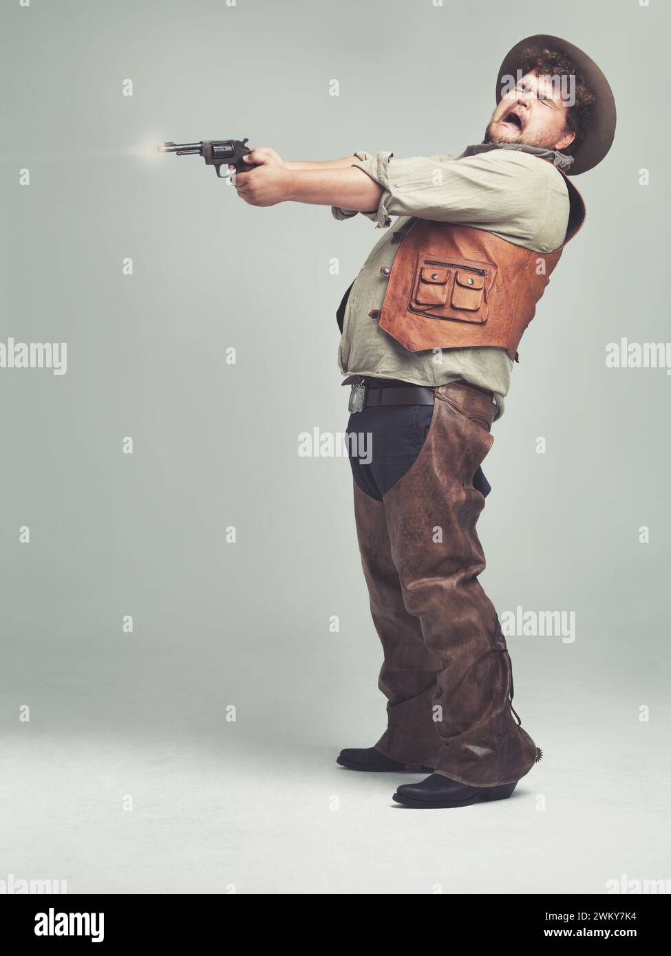 Cowboy, uomo e fucile in studio, pistola o combattimento occidentale isolati su uno spazio di mockup su sfondo bianco. Più grande, divertente criminale e persona con Foto Stock