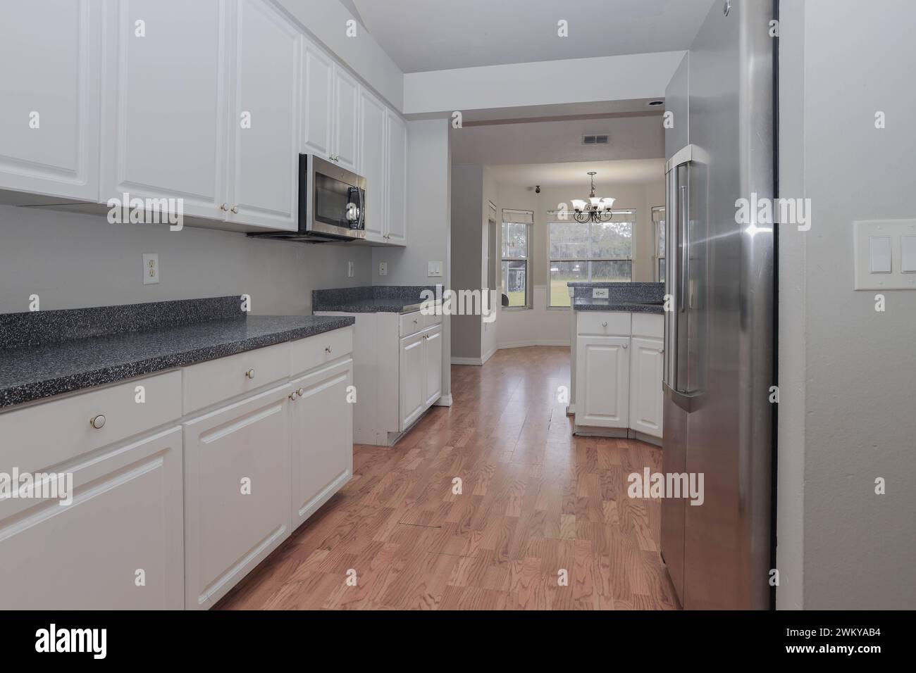 Una moderna cucina bianca con eleganti pavimenti in legno Foto Stock