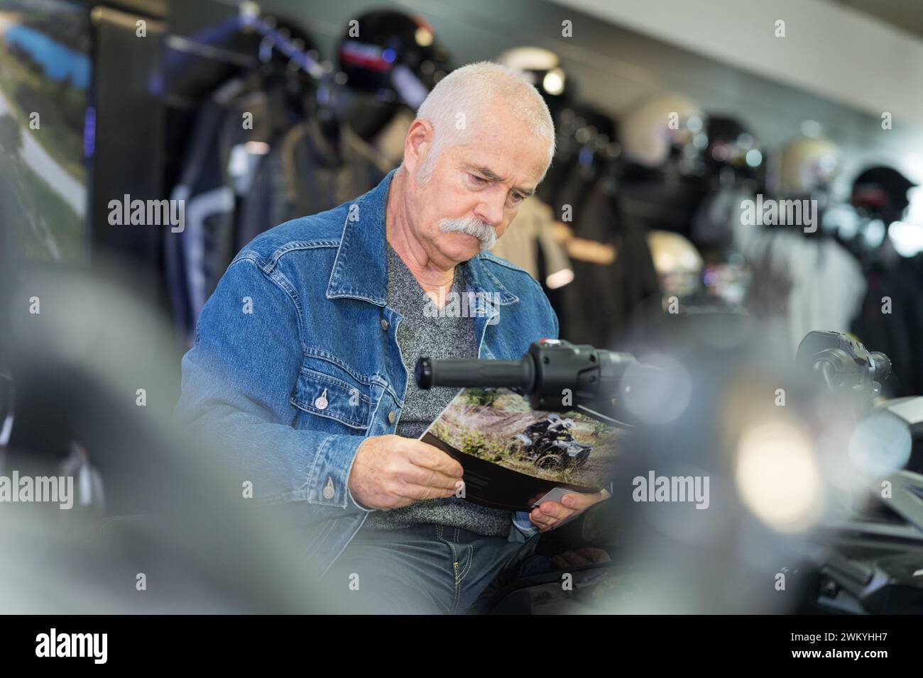 uomo che guarda il depliant in moto showroom Foto Stock