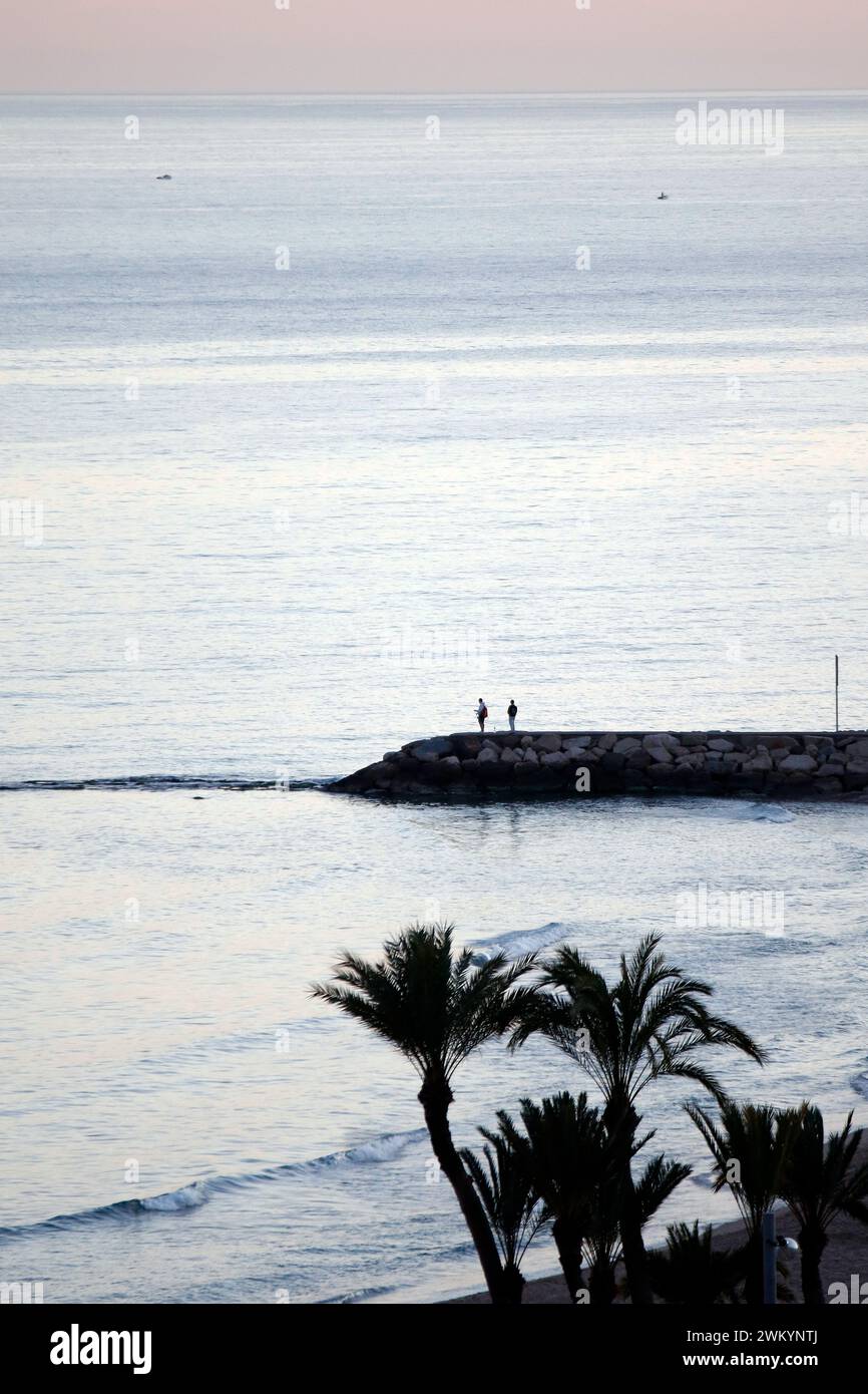 Gente sulla frangiflutti al tramonto a Villajoyosa Foto Stock