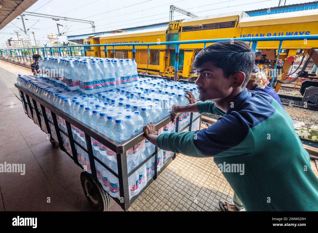 Il carico del carrello di acqua potabile in bottiglia viene spostato in una stazione ferroviaria indiana Foto Stock