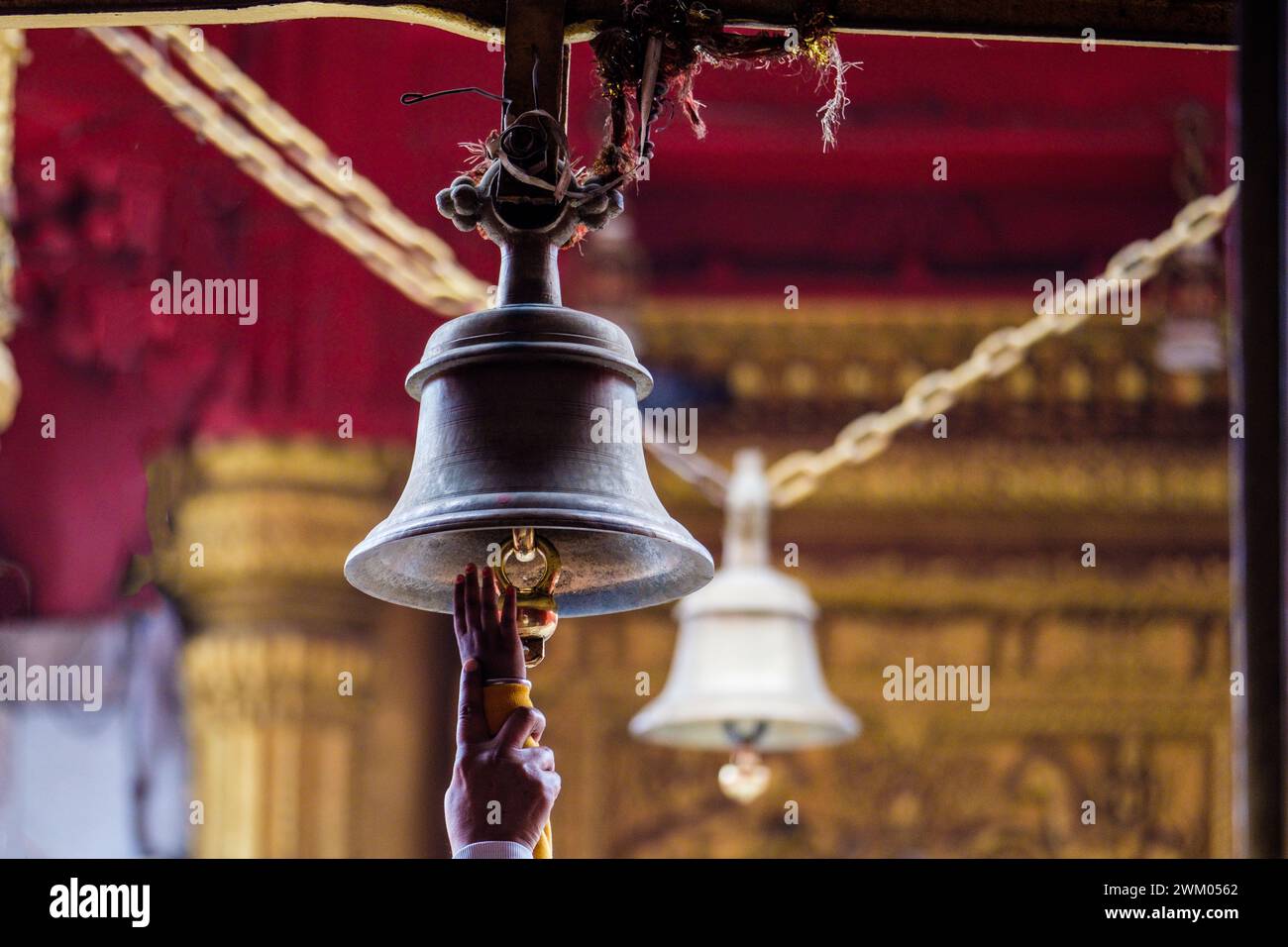 Devoto che raggiunge l'anello delle campane del Tempio in un tempio indù a Varanasi , India Foto Stock