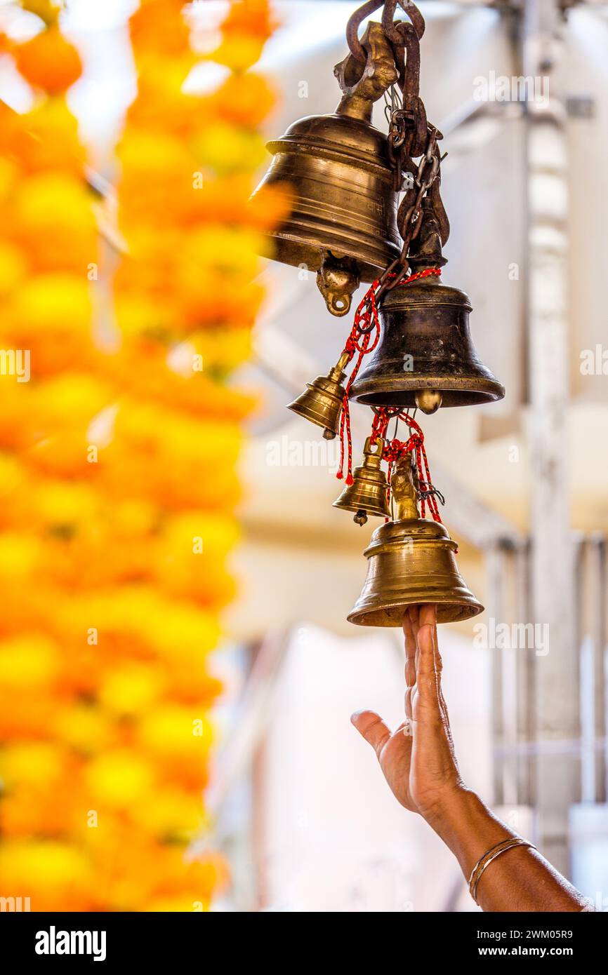 Devoto che raggiunge l'anello delle campane del Tempio in un tempio indù a Varanasi , India Foto Stock