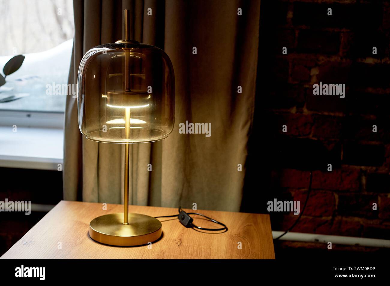 Un'interessante lampada di design su una base dorata con vetro spesso. Stile inglese. Interni classici Foto Stock