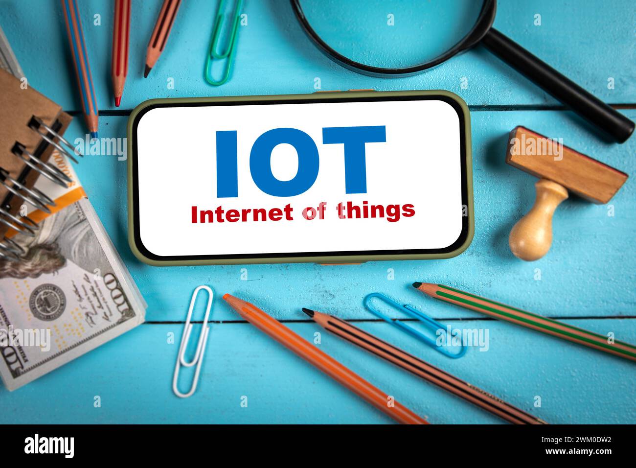 Concetto IOT dell'INTERNET delle cose. Telefono cellulare su un tavolo di legno blu. Foto Stock