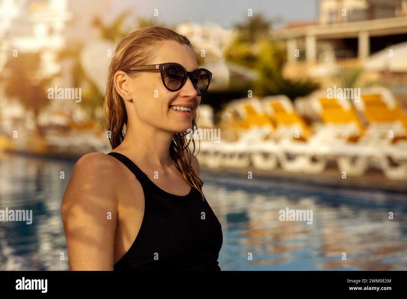 donna seduta e rilassante presso la piscina del resort al tramonto. vacanze estive Foto Stock