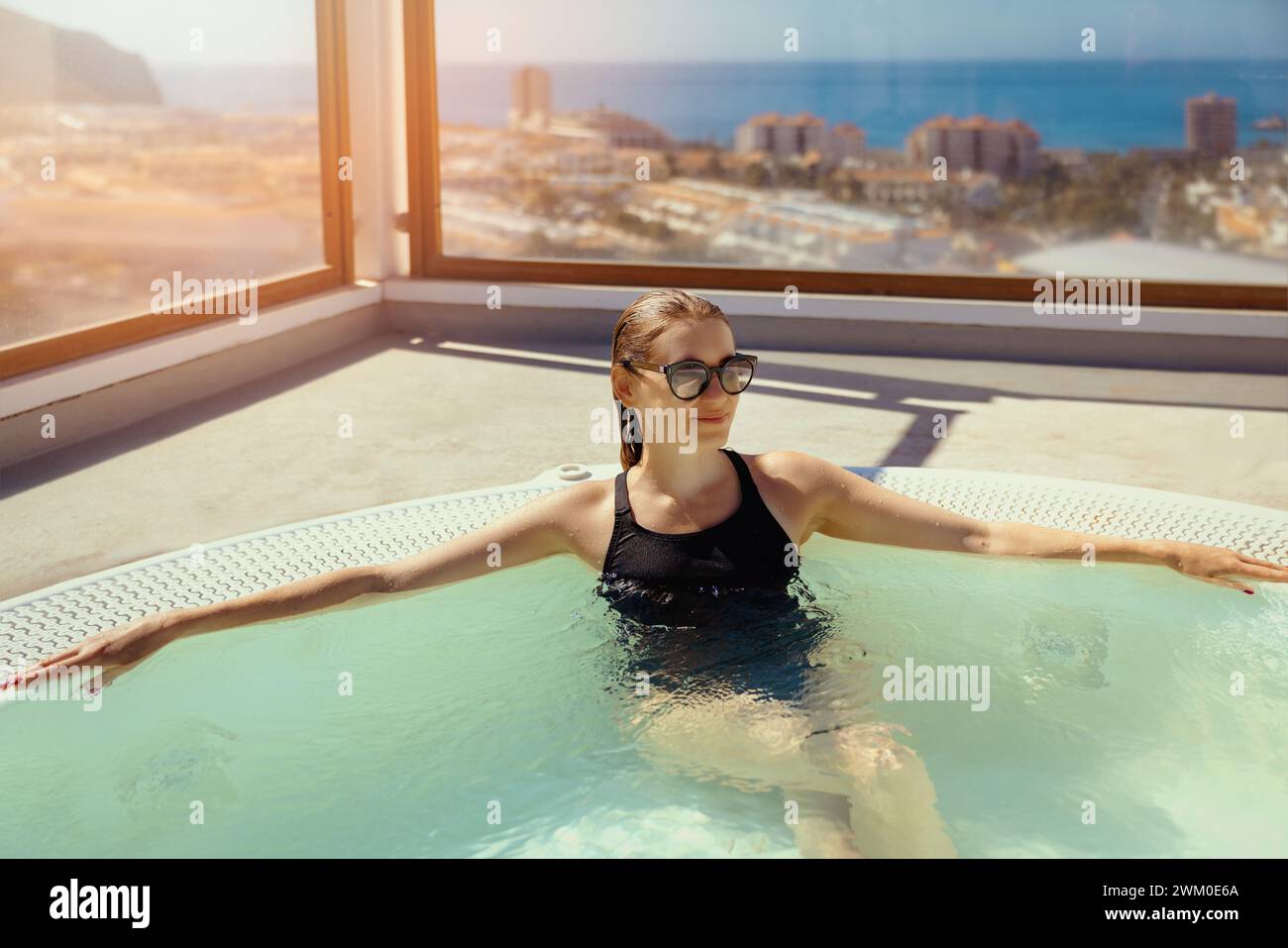 Donna che si rilassa nella jacuzzi sul tetto durante la giornata di sole nel resort di vacanza di Tenerife. viaggio breve Foto Stock