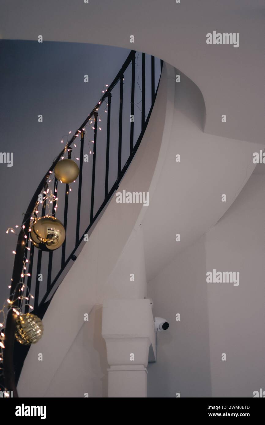 Ringhiera in metallo decorata con ornamenti natalizi accanto a una scala Foto Stock