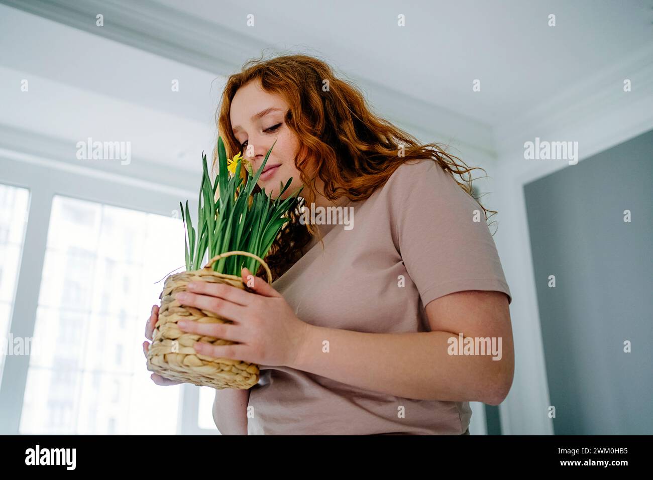 Donna rossa che puzza di fiori di narcisi a casa Foto Stock