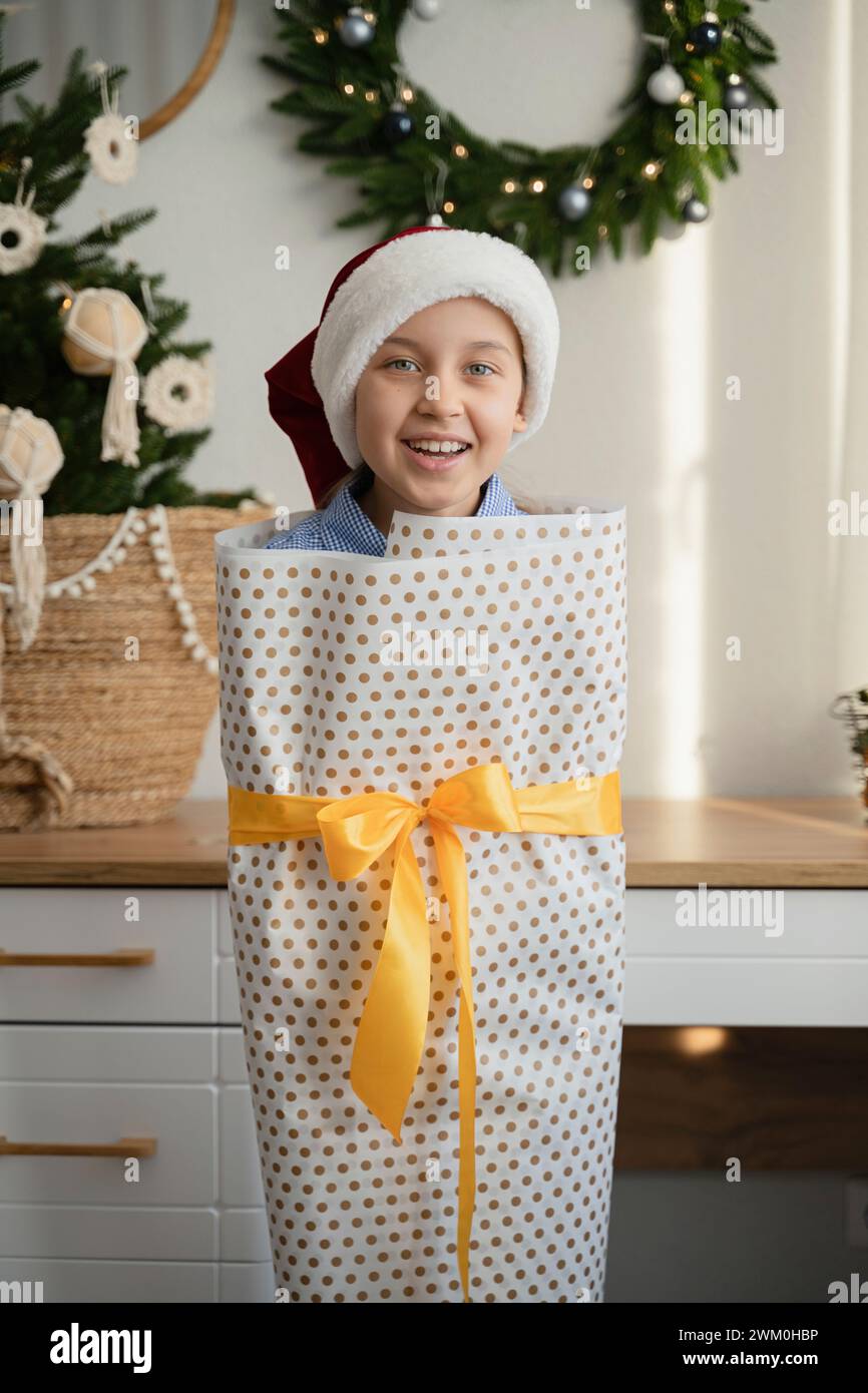 Una ragazza giocosa avvolta in un giornale di Natale a casa Foto Stock
