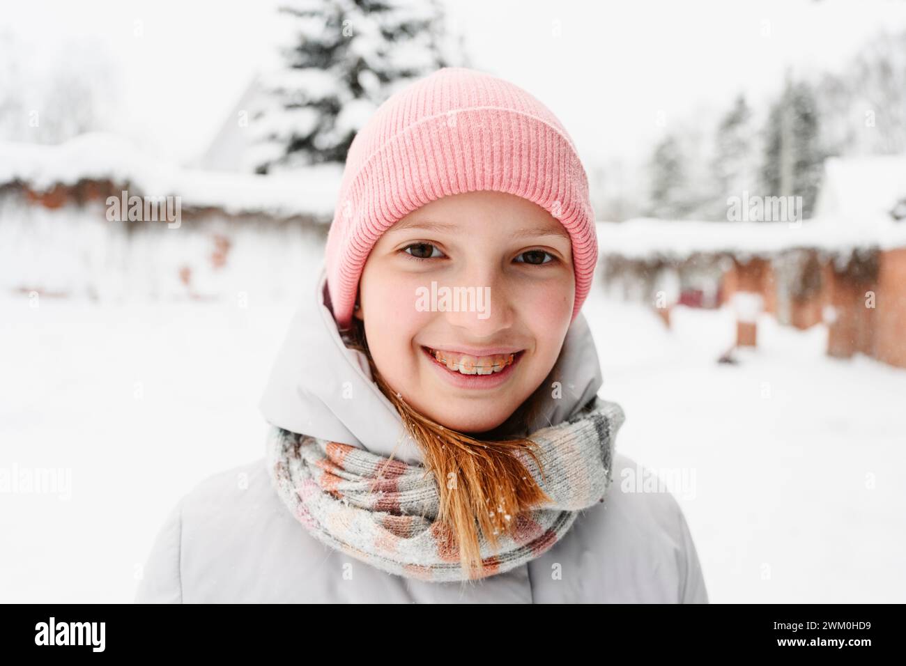 Ragazza sorridente con l'apparecchio che indossa abiti caldi in inverno Foto Stock