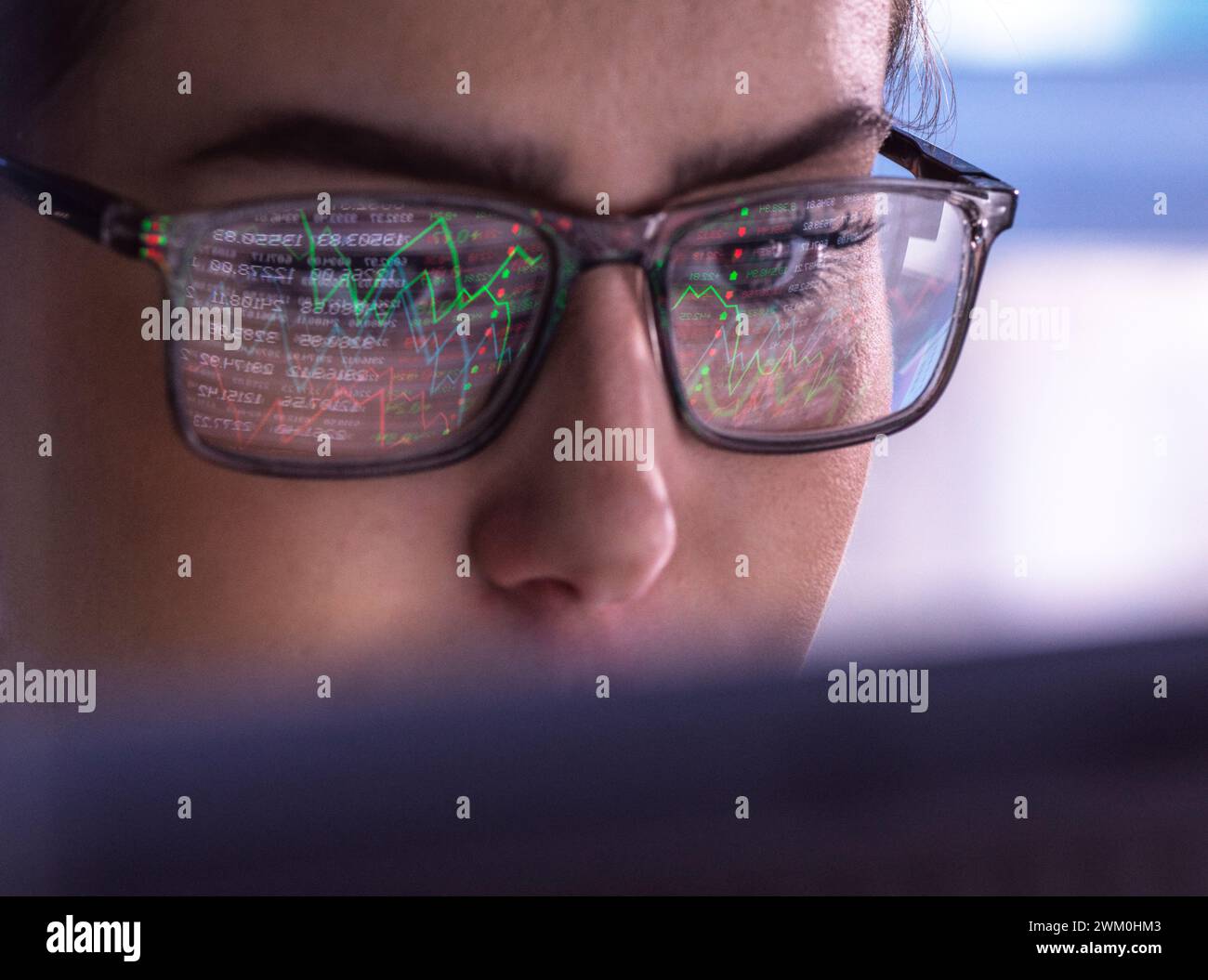 Donna d'affari che indossa occhiali che analizza i dati dei mercati finanziari al computer Foto Stock