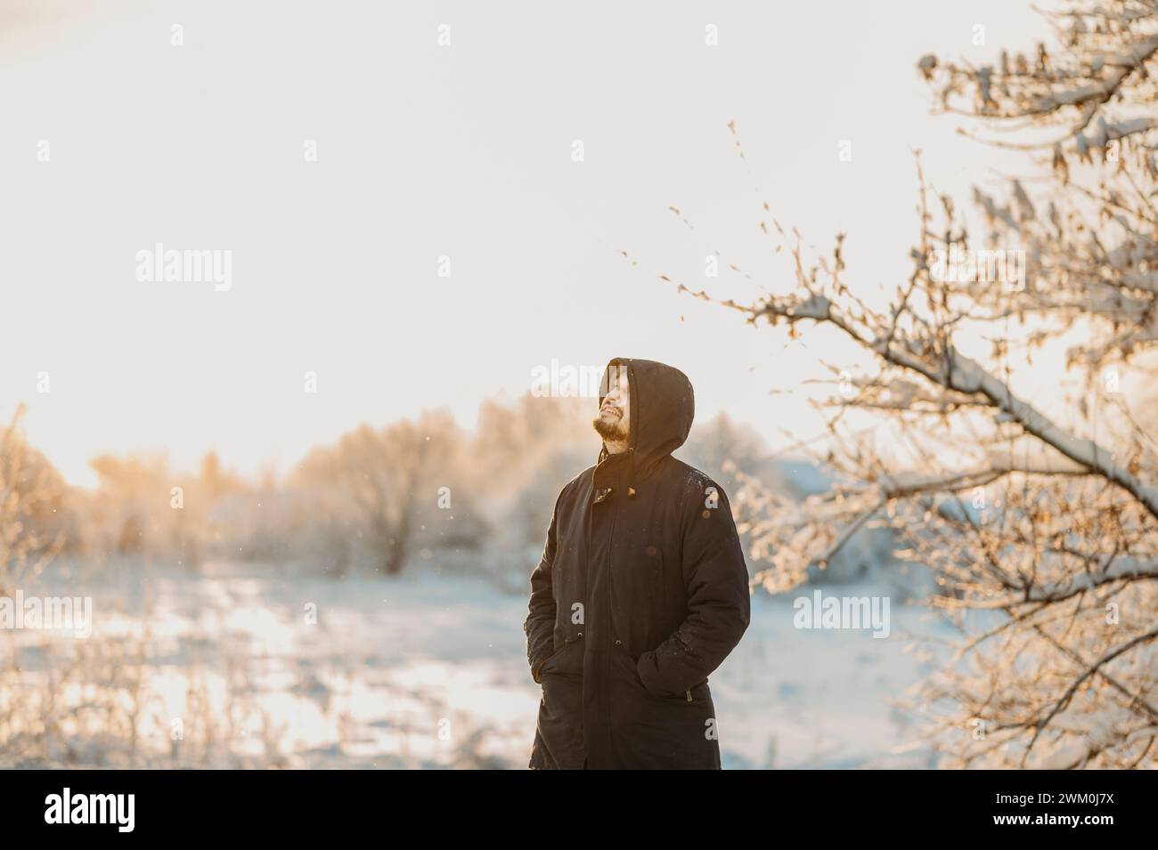 Uomo che indossa una giacca invernale e si trova in piedi nella foresta Foto Stock