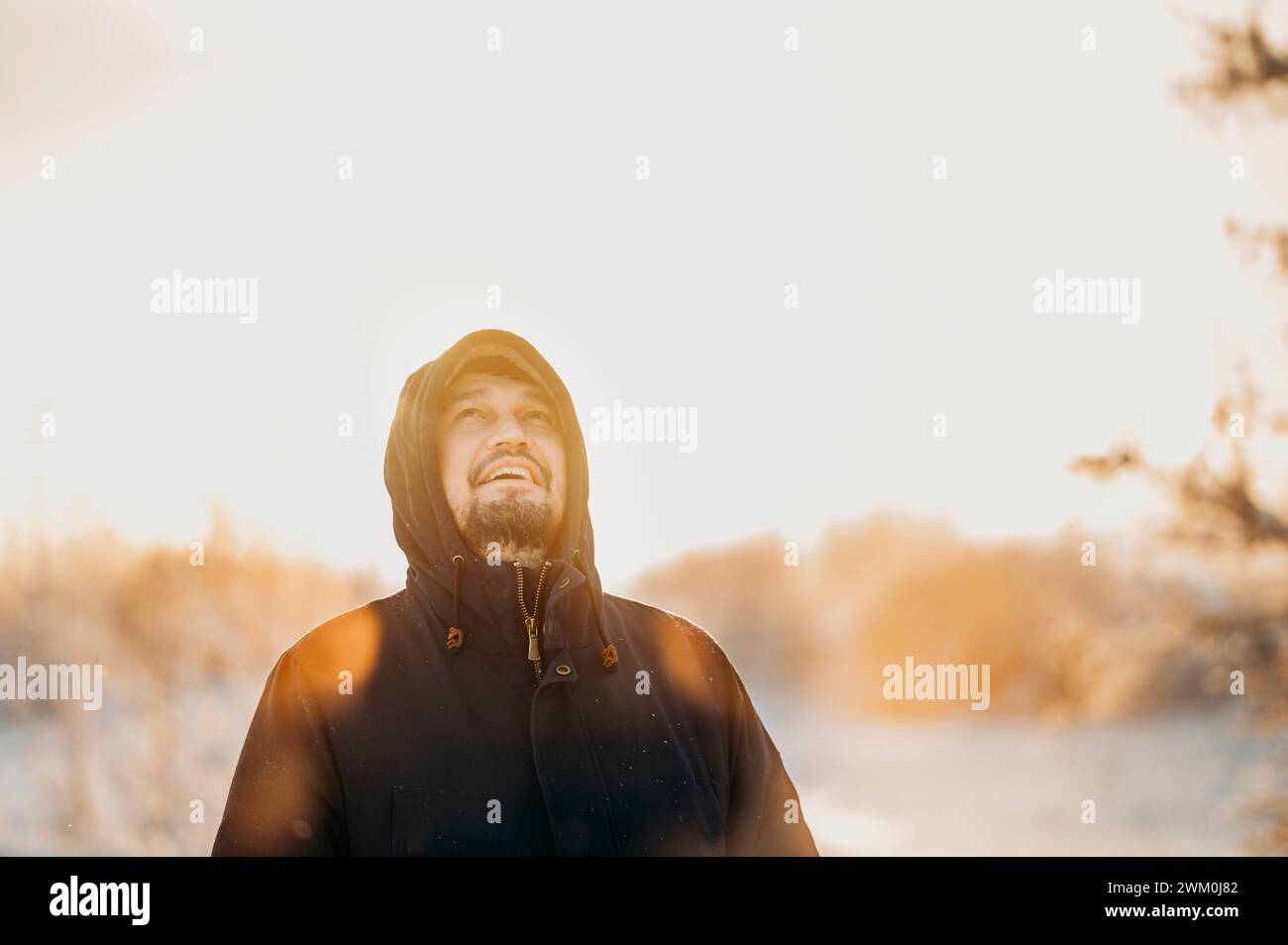 Uomo maturo che indossa una giacca invernale nella foresta nelle giornate di sole Foto Stock