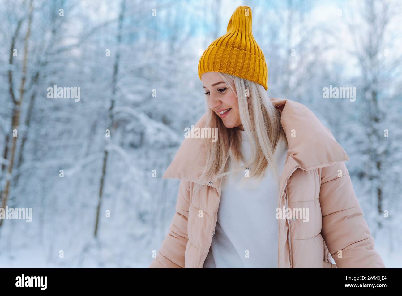 Donna sorridente che indossa una giacca invernale nella foresta Foto Stock