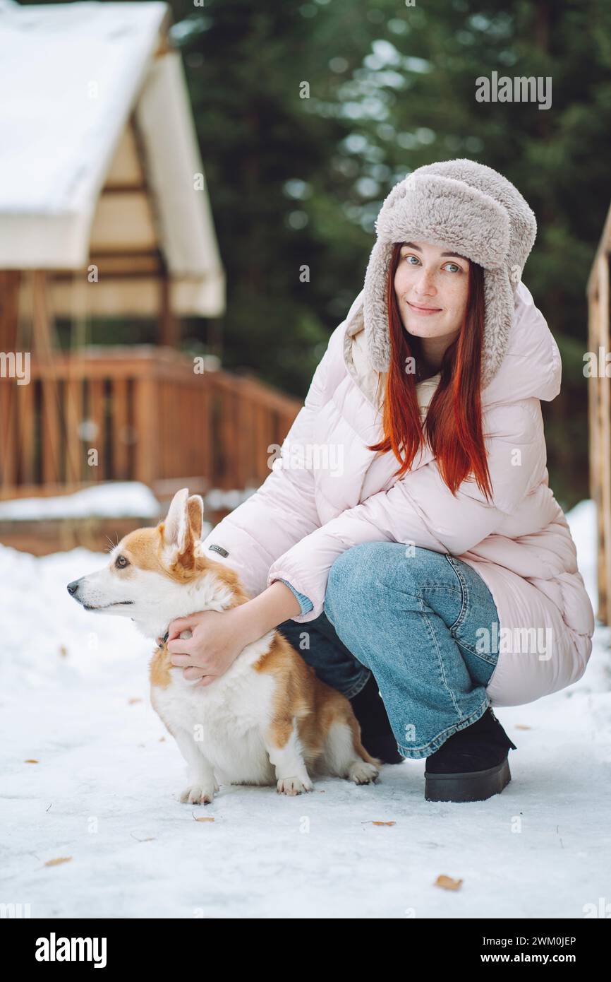 Donna che indossa abiti caldi e tiene in mano il cane Corgi in inverno Foto Stock