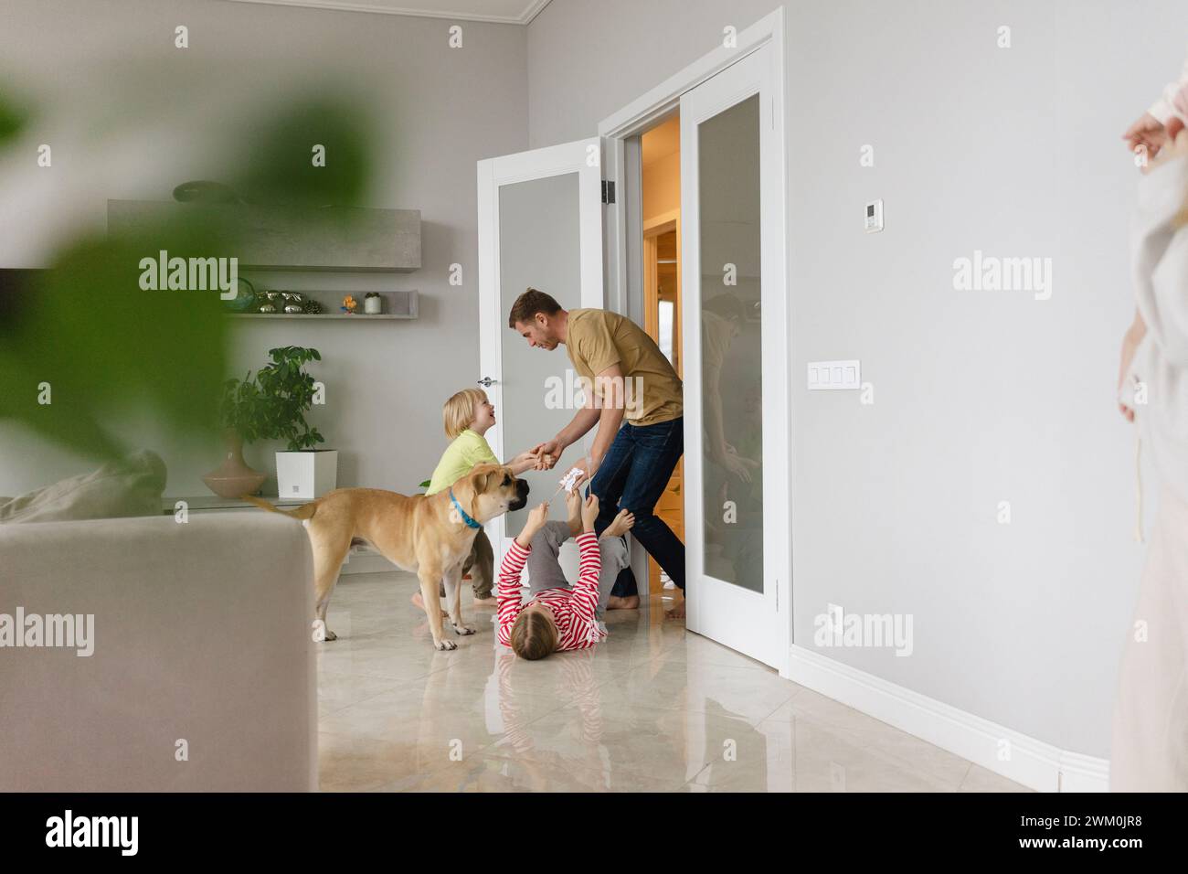 Bambini giocosi che accolgono il padre alla porta Foto Stock