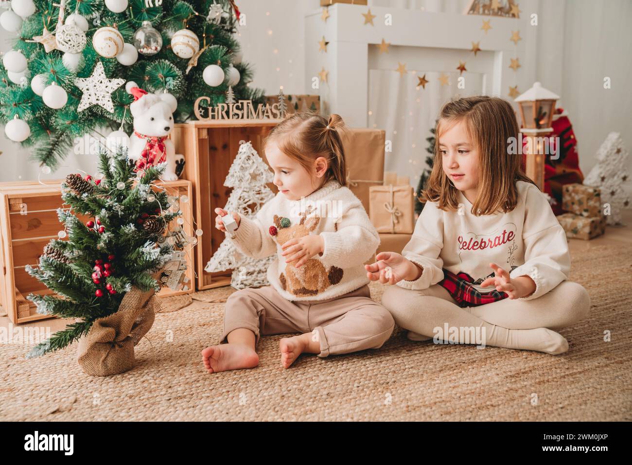 Ragazze che giocano e decorano un piccolo albero di Natale a casa Foto Stock