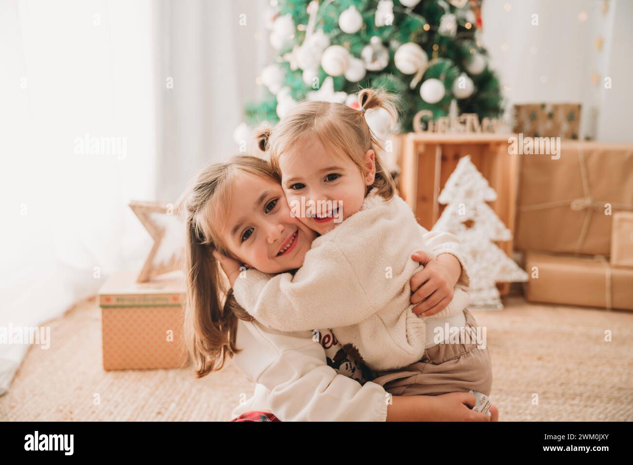 Ragazza che abbraccia sorella in salotto a casa Foto Stock