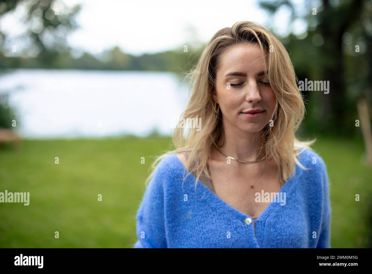 Donna bionda sorridente con capelli biondi e occhi chiusi Foto Stock
