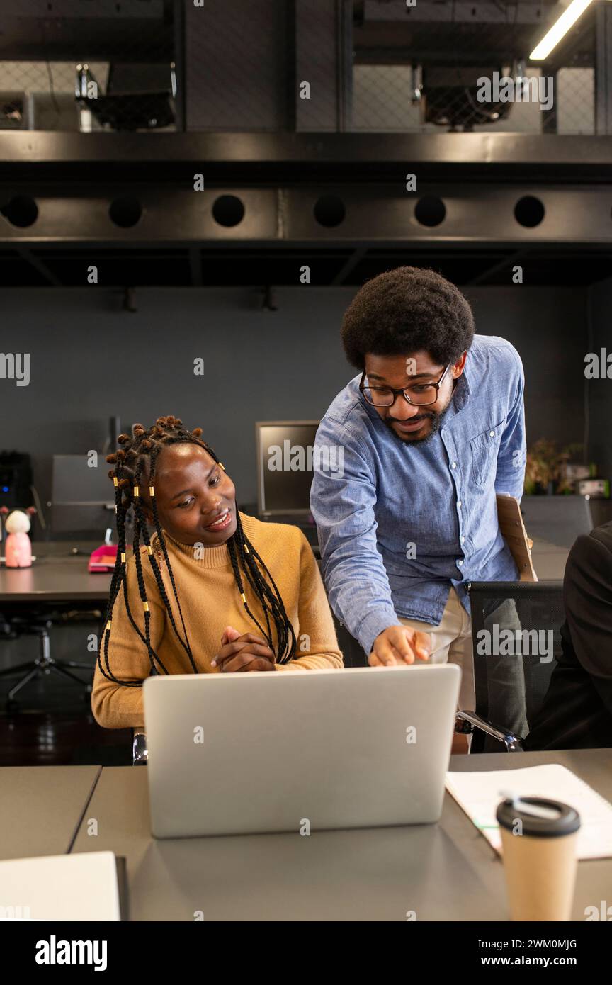 Giovane uomo d'affari che parla di laptop in ufficio Foto Stock