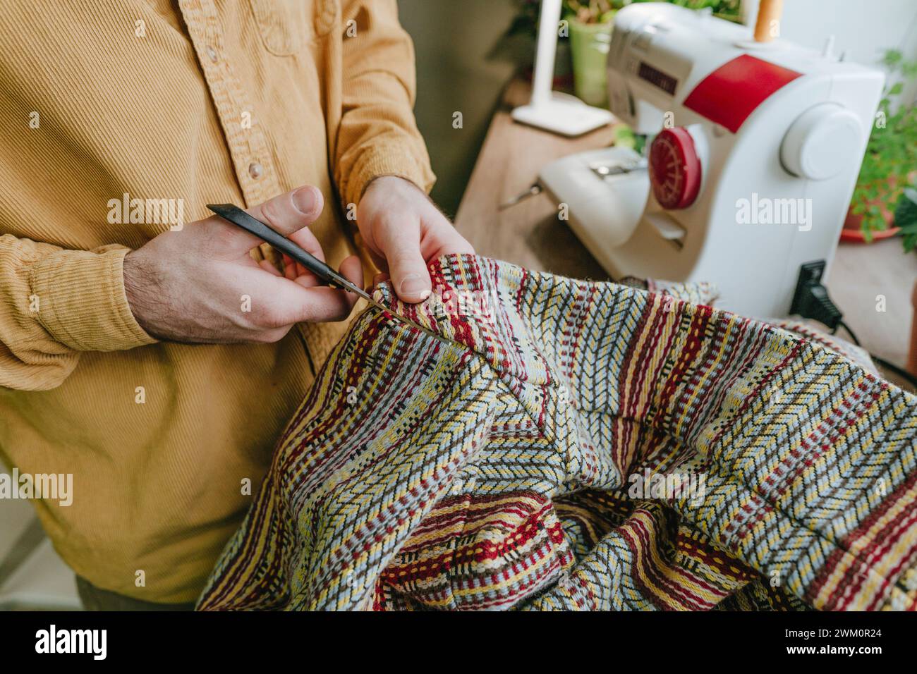 Uomo che taglia un panno con le forbici a casa Foto Stock