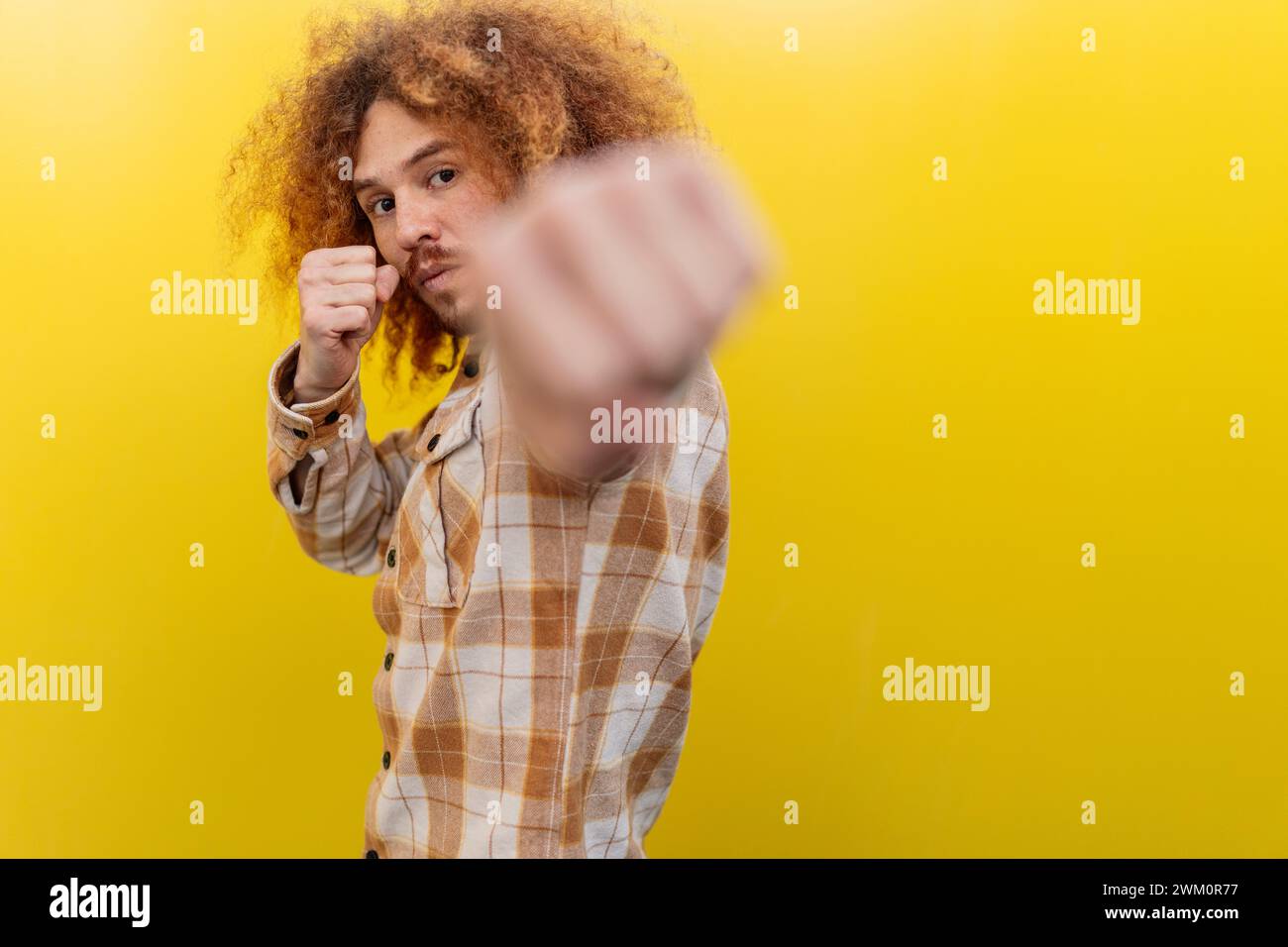 Uomo che pugni davanti al muro giallo Foto Stock