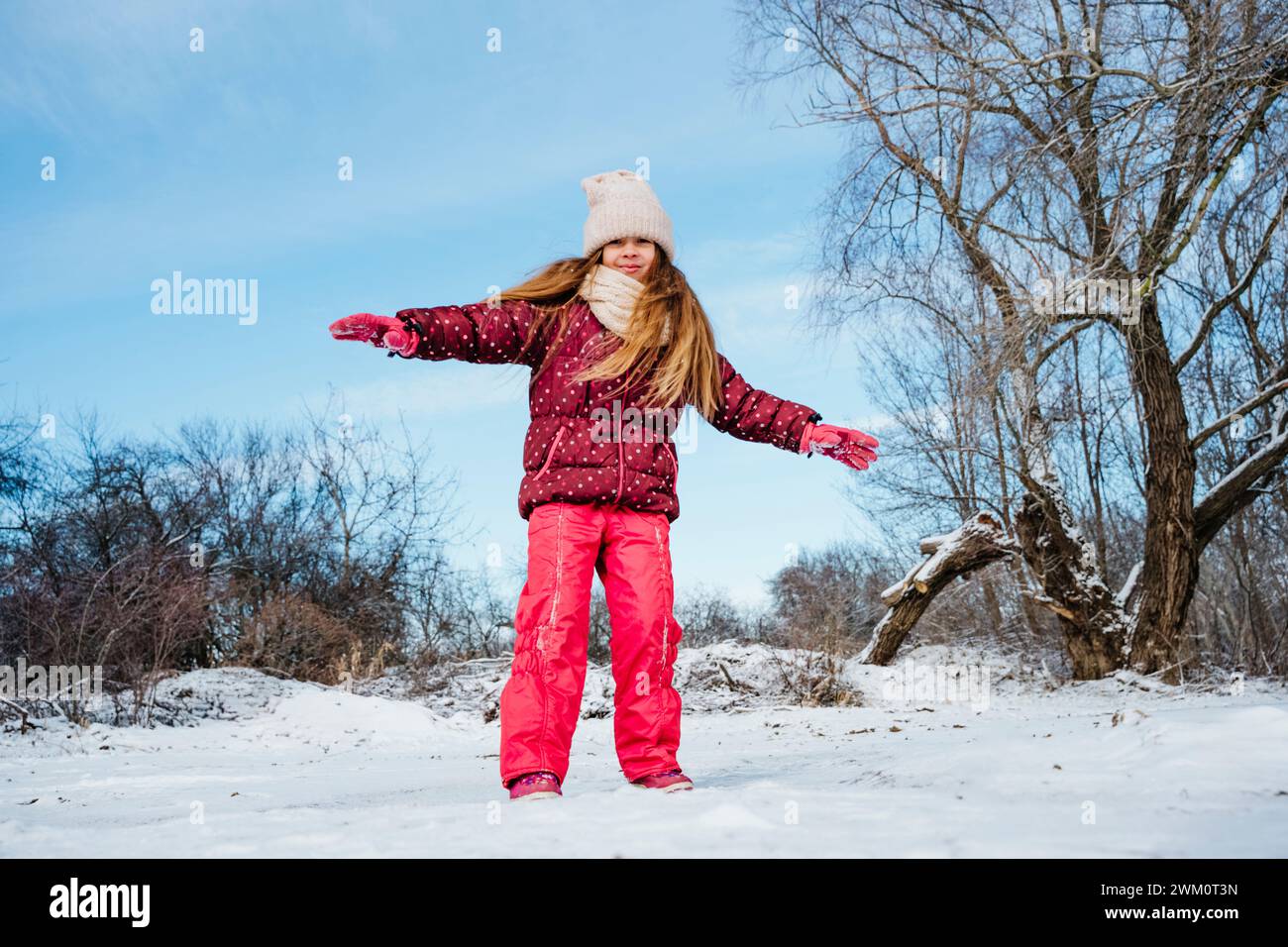 Ragazza felice in piedi con le braccia allungate sulla neve in inverno Foto Stock