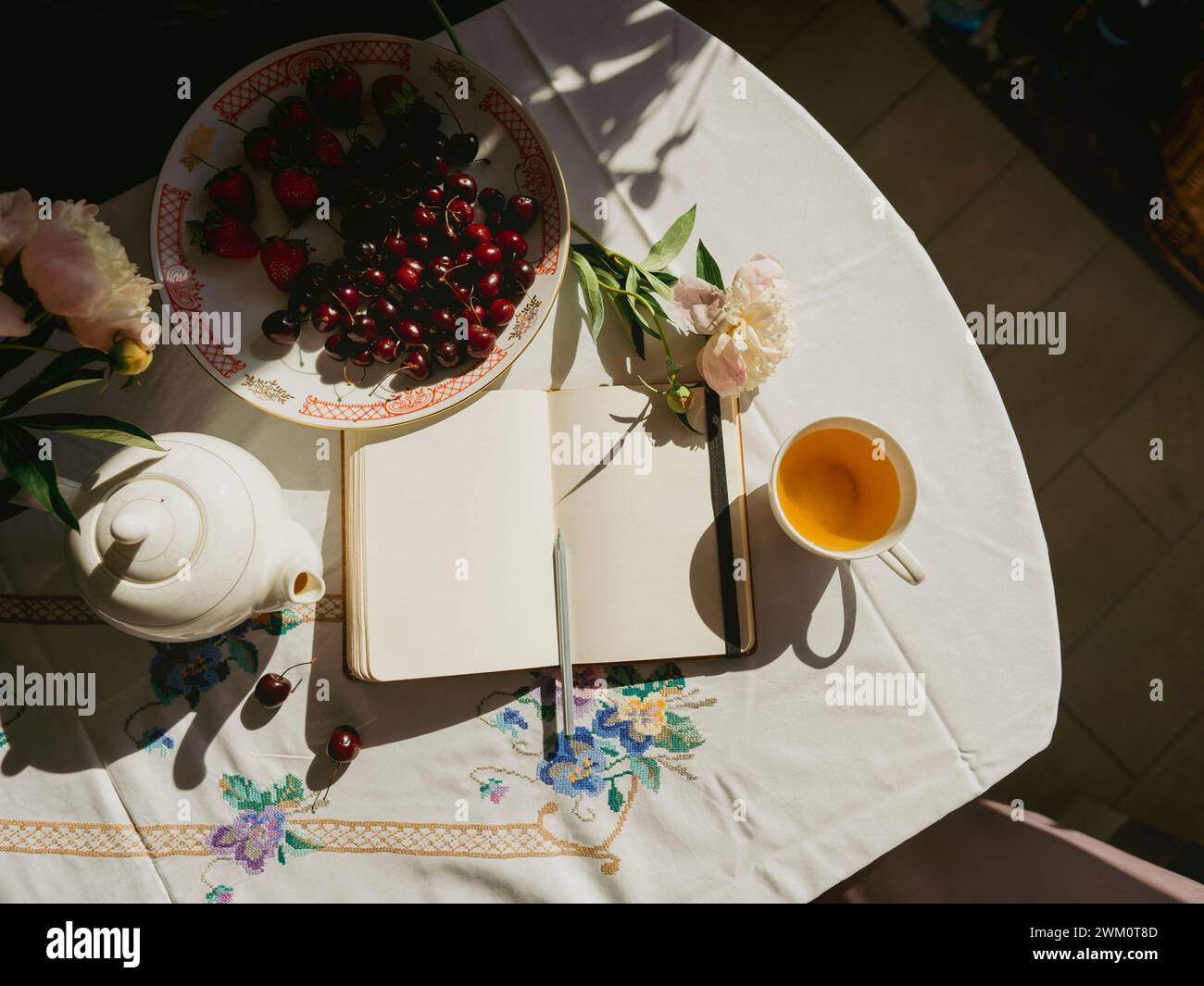Diario vicino alla teiera e alla frutta sul tavolo a casa Foto Stock