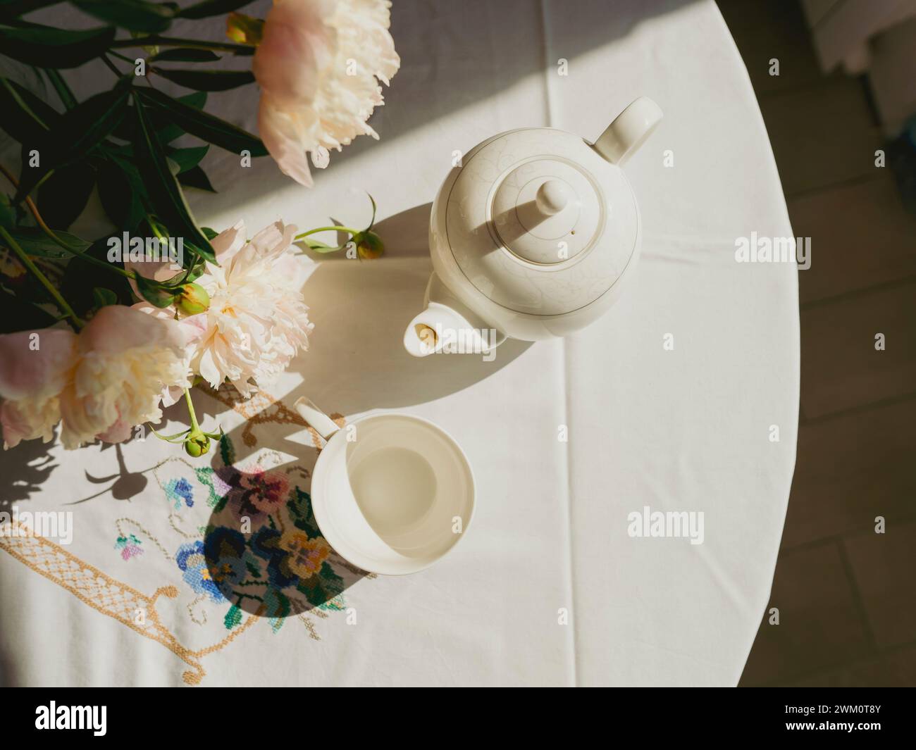 Teiera in porcellana e tazza vicino ai fiori sul tavolo Foto Stock