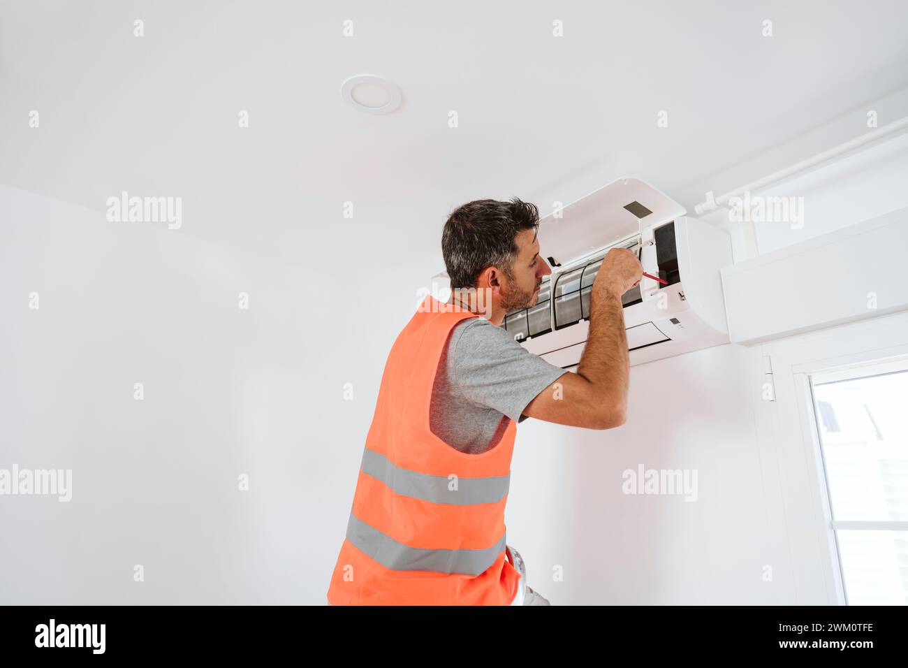 Elettricista che ripara il condizionatore d'aria a casa Foto Stock