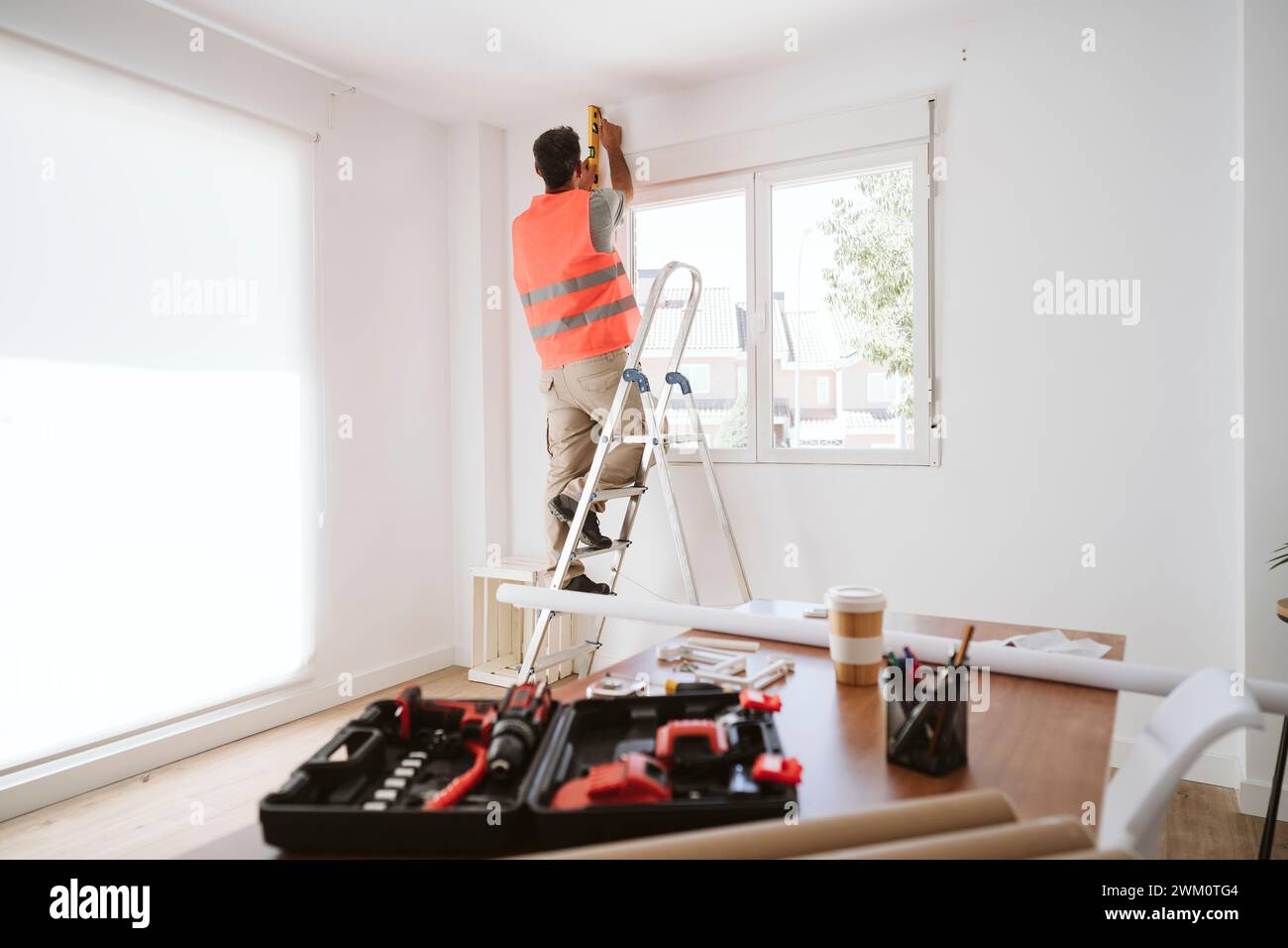 Tecnico maturo che lavora vicino al finestrino a casa Foto Stock