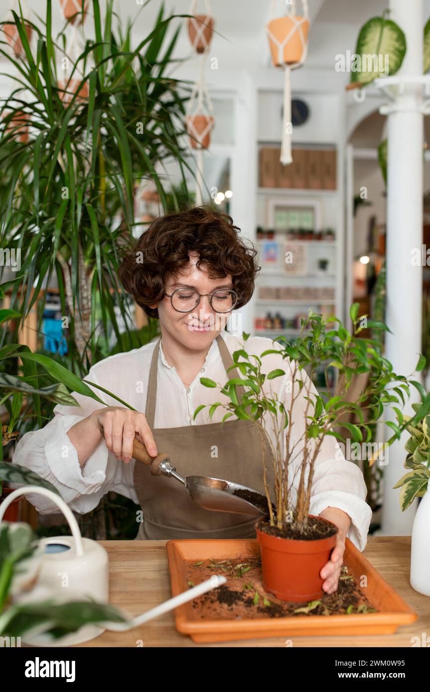 Impianto di vasatura botanico sorridente con pala in negozio Foto Stock