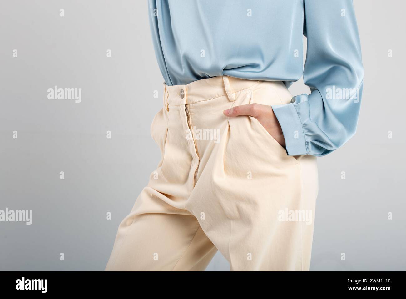 Modello alla moda in pantaloni beige e blusa blu con tasca a mano su sfondo isolato. Adatto per gli annunci di moda. Foto Stock