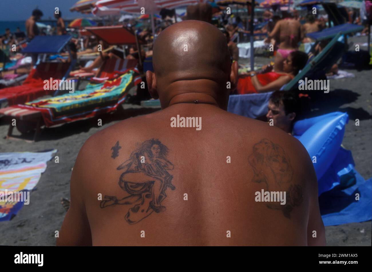 4066277 Lido di Ostia, Italia; (add.info.: Ostia Lido, 1999. Uomo tatuato. Ostia è una città balneare vicino a Roma. Nel periodo estivo molti abitanti di Roma si recano al mare, in particolare i giovani della periferia, hanno detto nello slang 'coatti' / Lido di Ostia, 1999. Uomo tatuato. Ostia è la spiaggia dei romani. D'estate è frequentata in particolare dai giovani che abitano le borgate della periferia, i cosiddetti "coatti"-); © Marcello Mencarini. Tutti i diritti riservati 2024. Foto Stock