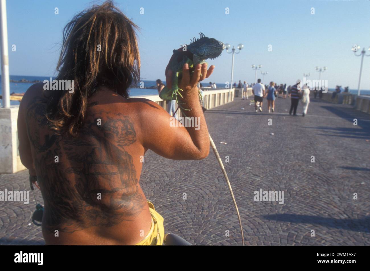 4066275 Lido di Ostia, Italia; (add.info.: Ostia Lido, 1999. Uomo tatuato con iguana. Ostia è una città balneare vicino a Roma. Nel periodo estivo molti abitanti di Roma si recano al mare, in particolare i giovani della periferia, hanno detto nello slang 'coatti' / Lido di Ostia, 1999. Uomo tatuato con iguana. Ostia è la spiaggia dei romani. D'estate è frequentata in particolare dai giovani che abitano le borgate della periferia, i cosiddetti "coatti"-); © Marcello Mencarini. Tutti i diritti riservati 2024. Foto Stock