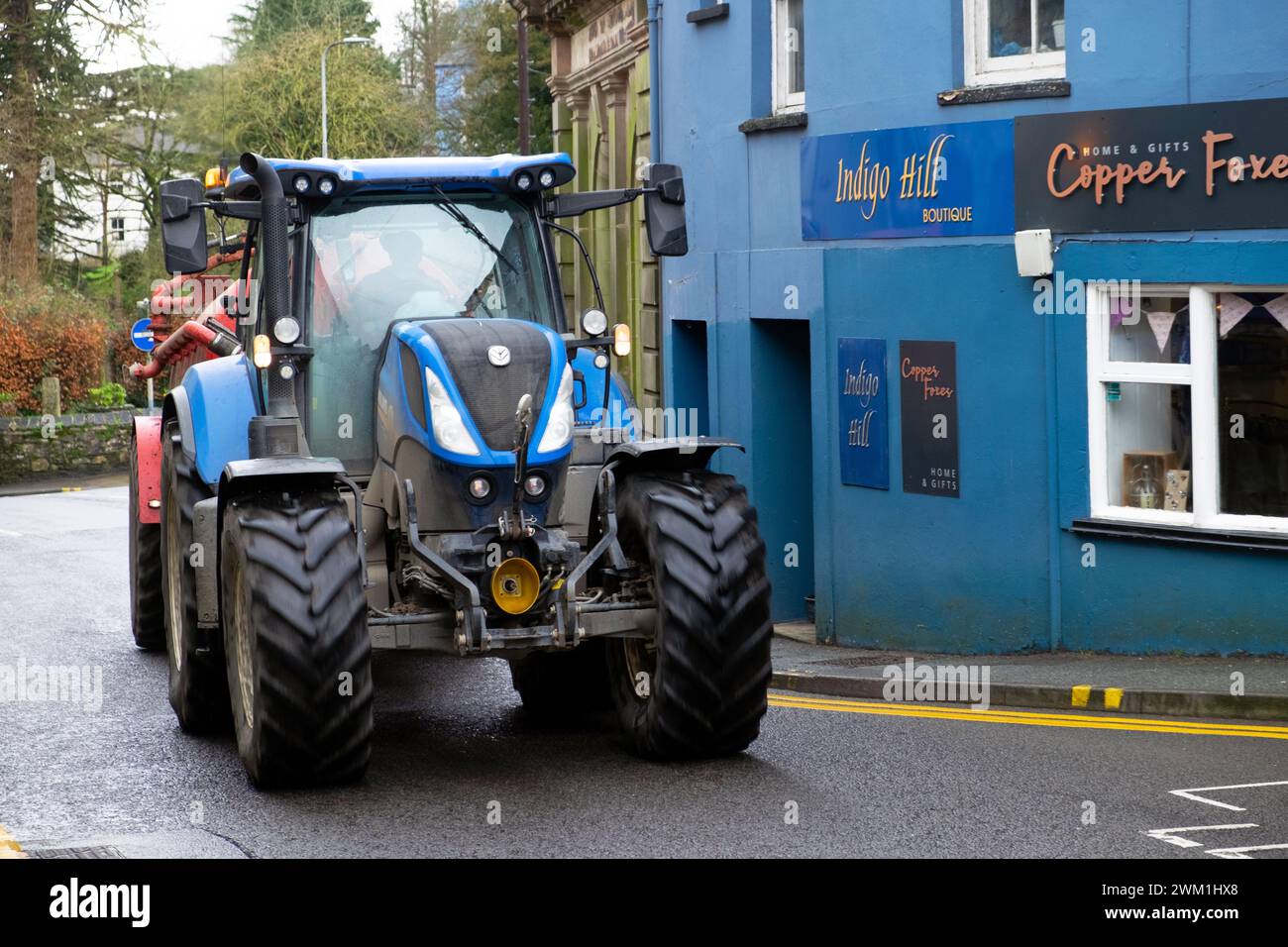 Blue Tractor che guida lungo Rhosmaen Street fuori dai negozi attraverso la città di Llandeilo Carmarthenshire Galles Regno Unito Gran Bretagna 2024 KATHY DEWITT Foto Stock