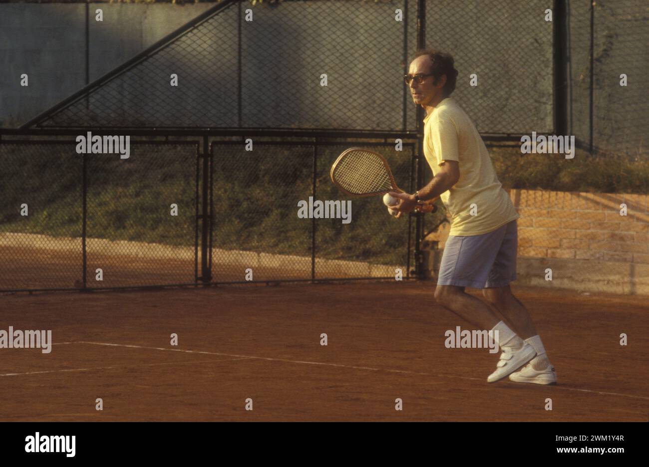 MME4745320 Jean-Luc Godard che gioca a tennis, 1983 (foto); (add.info.: Mostra del Cinema di Venezia, 1983. Jean-Luc Godard, regista svizzero francese, che gioca nel campo da tennis dell'Excelsior Hotel/Mostra del Cinema di Venezia. Ha registrato Jean-Luc Godard con il tennis ai campi dell'Hotel Excelsioer -); © Marcello Mencarini. Tutti i diritti riservati 2024. Foto Stock