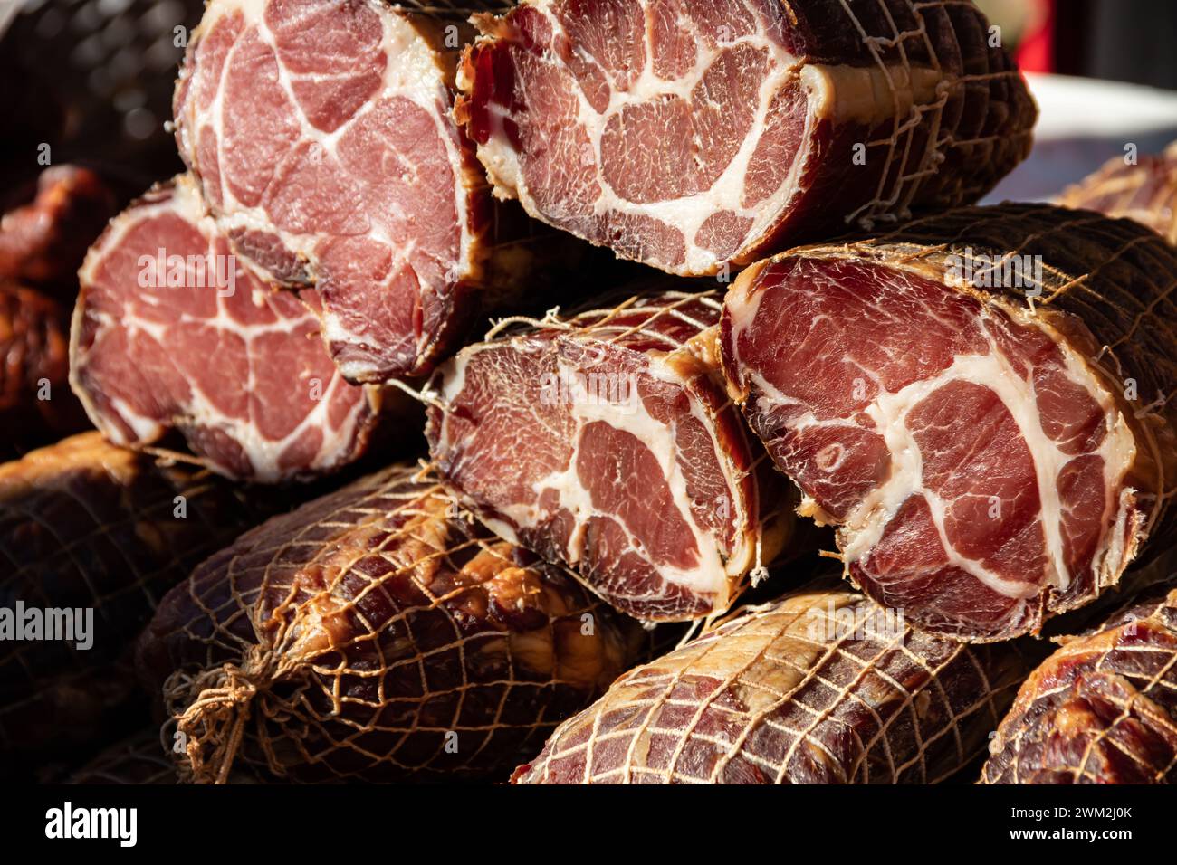 Deliziosi pezzi di carne affumicata esposti per la vendita nel mercato presentato in vendita in un mercato agricolo nel villaggio di Kacarevo, festival del bacon gastronomico Foto Stock