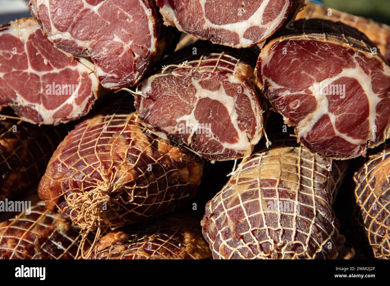 Deliziosi pezzi di carne affumicata esposti per la vendita nel mercato presentato in vendita in un mercato agricolo nel villaggio di Kacarevo, festival del bacon gastronomico Foto Stock