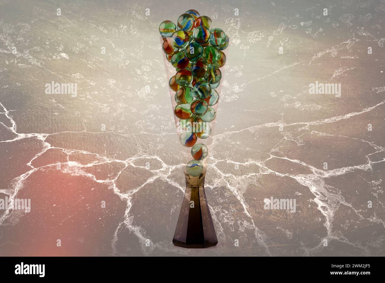 Primo piano di un bicchiere di champagne riempito di biglie di vetro isolate su uno sfondo colorato Foto Stock