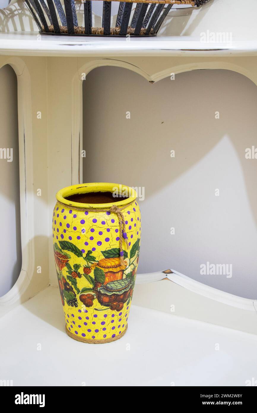 Vaso giallo con fiori viola e cestino di frutta Foto Stock