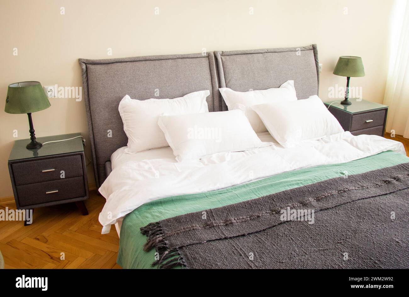Camera spaziosa con comodo letto, cuscini, coperte e due lampade Foto Stock