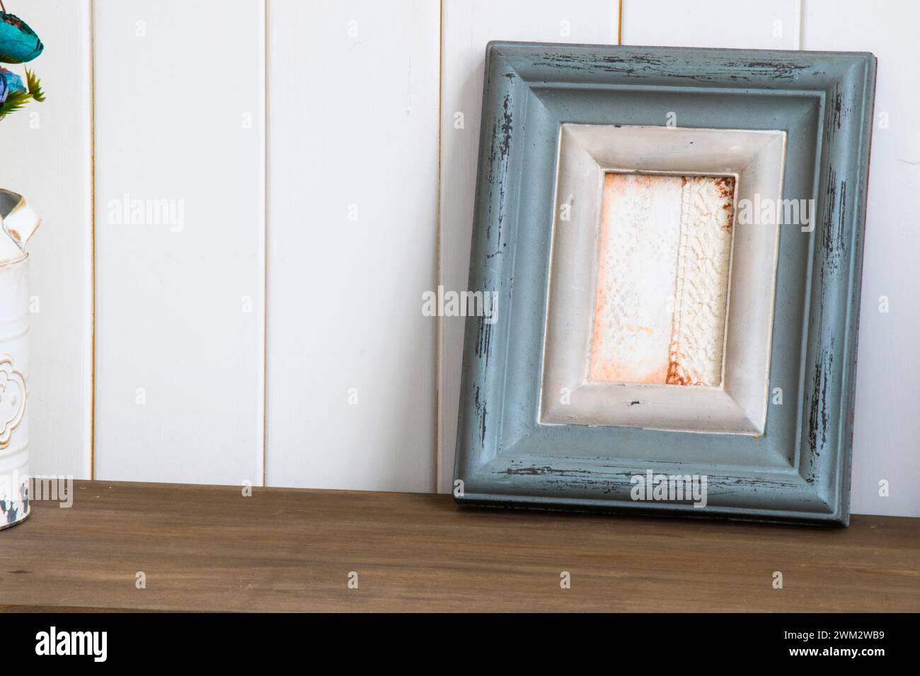 Un piccolo vaso di fiori su un tavolo di legno accanto alla cornice Foto Stock
