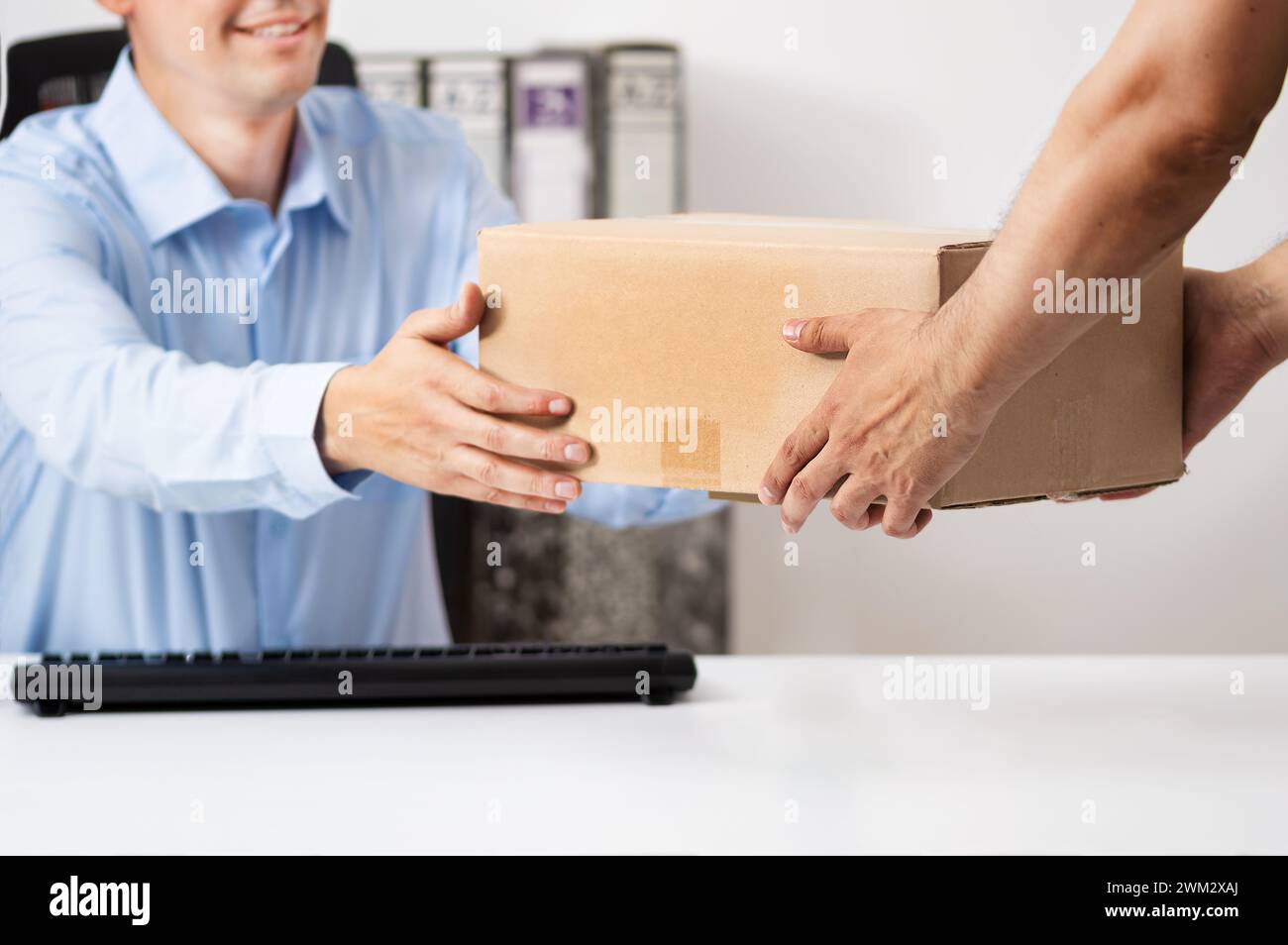 Uomo d'affari felice che riceve un pacco seduto su una scrivania in ufficio Foto Stock