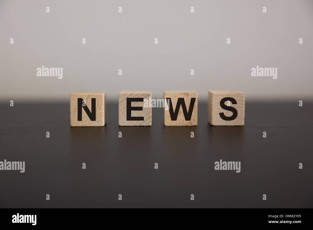 Cubo in legno su una superficie in cemento con testo News. finanziario, investimenti, economia. copia lo spazio a destra per la tua progettazione, sfondo grigio. Foto Stock