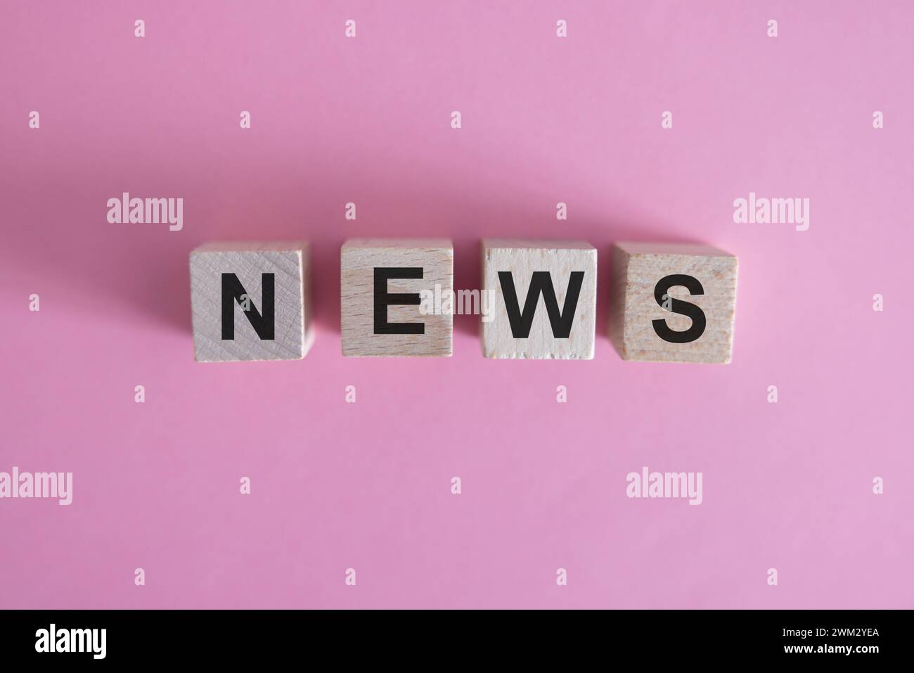 Cubo in legno su una superficie in cemento con testo News. finanziario, investimenti, economia. copia lo spazio a destra per la tua progettazione, sfondo grigio. Foto Stock