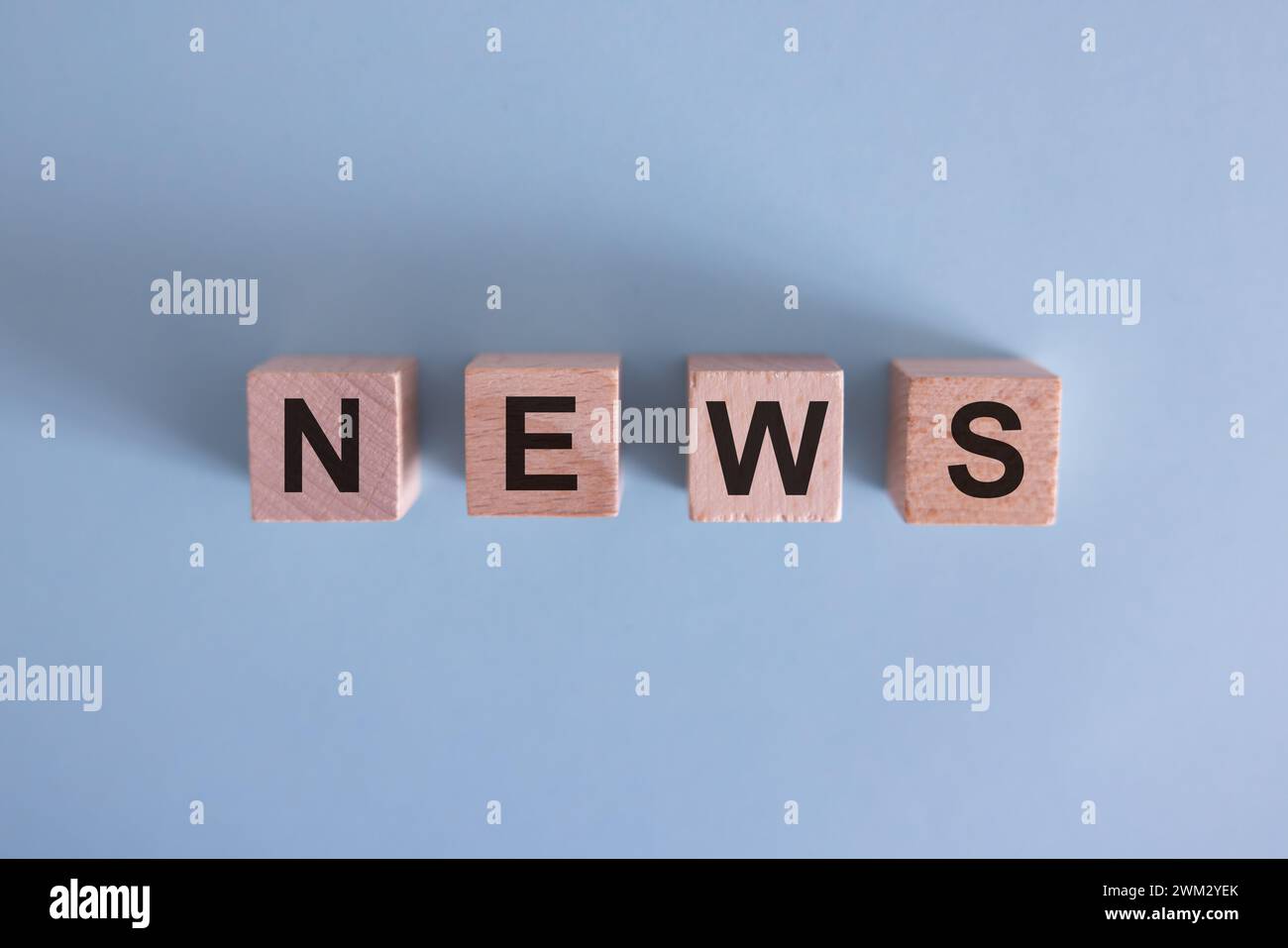 Cubo in legno su una superficie in cemento con testo News. finanziario, investimenti, economia. copia lo spazio a destra per la tua progettazione, sfondo grigio. Foto Stock